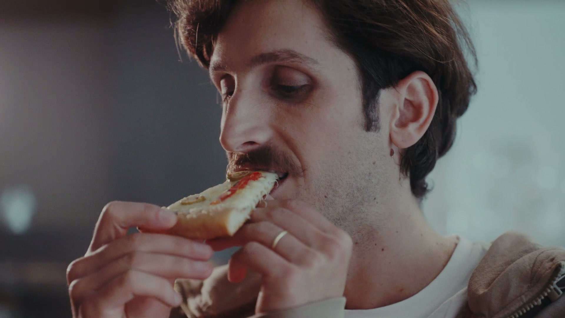 Hombre dando un mordisco a un sándwich, con expresión de gusto