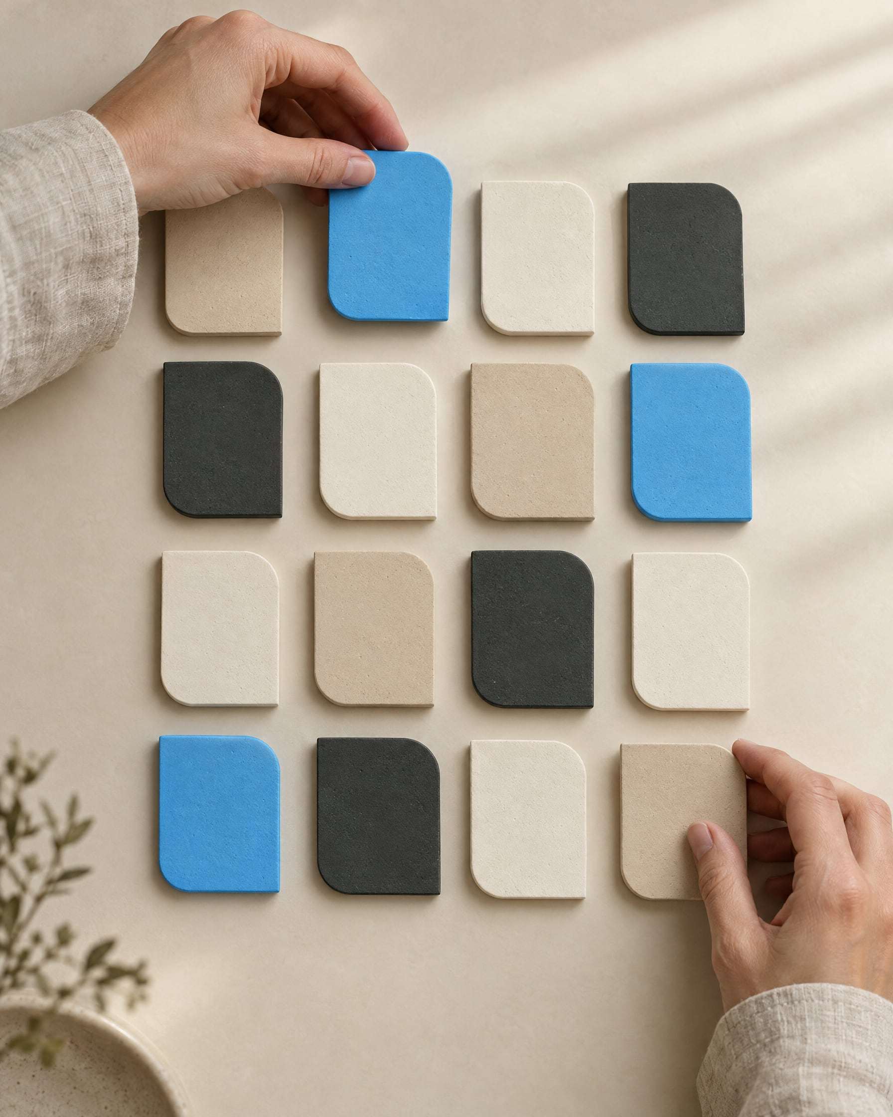Primer plano de manos ordenando placas de yeso mate en una grilla, como un calendario de contenidos