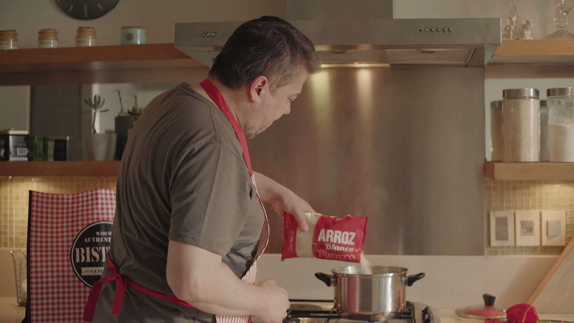 Hombre con delantal cocinando arroz en una cocina luminosa