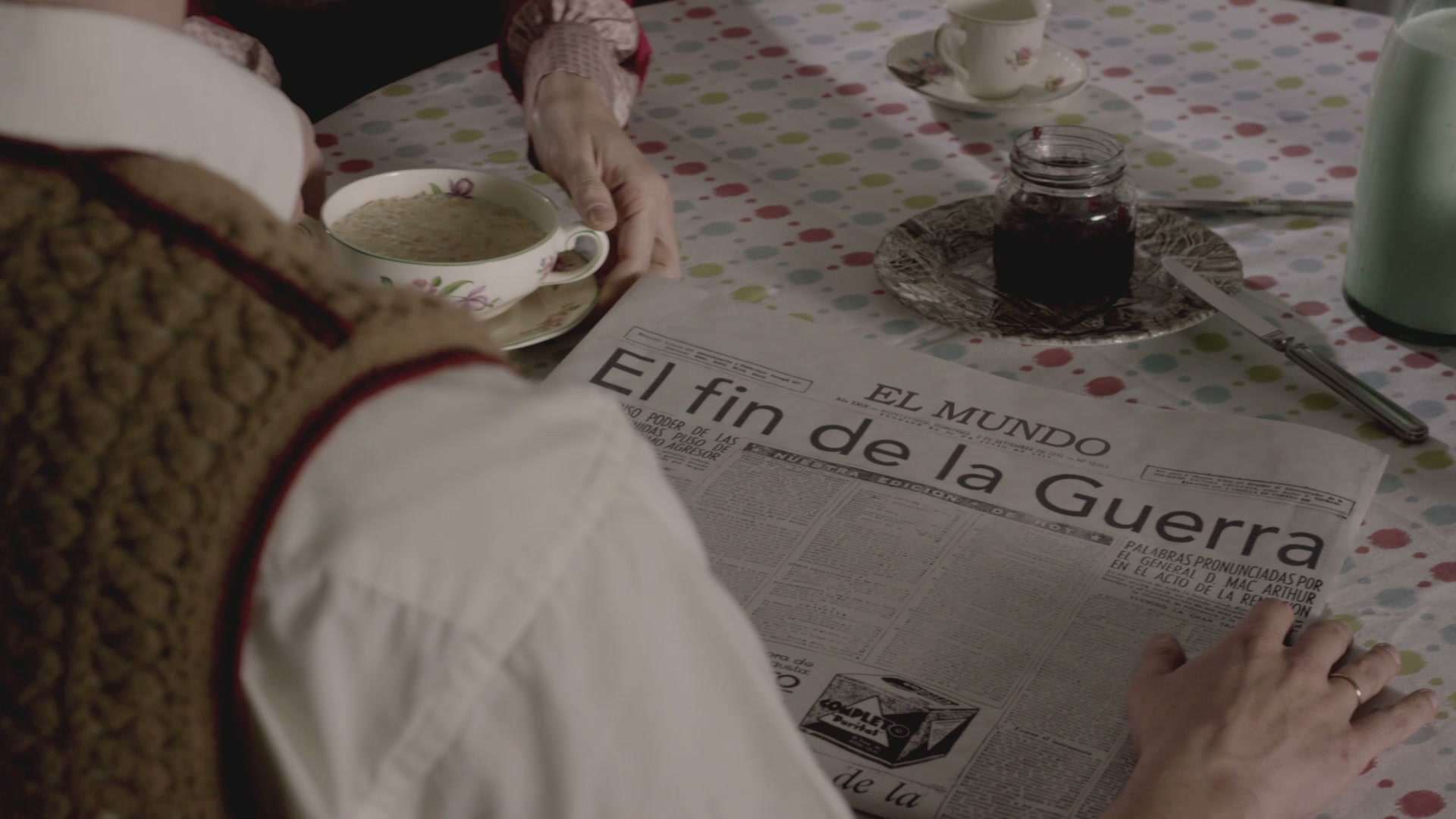 Mano sobre un diario de época con el titular «El fin de la Guerra» junto a una taza