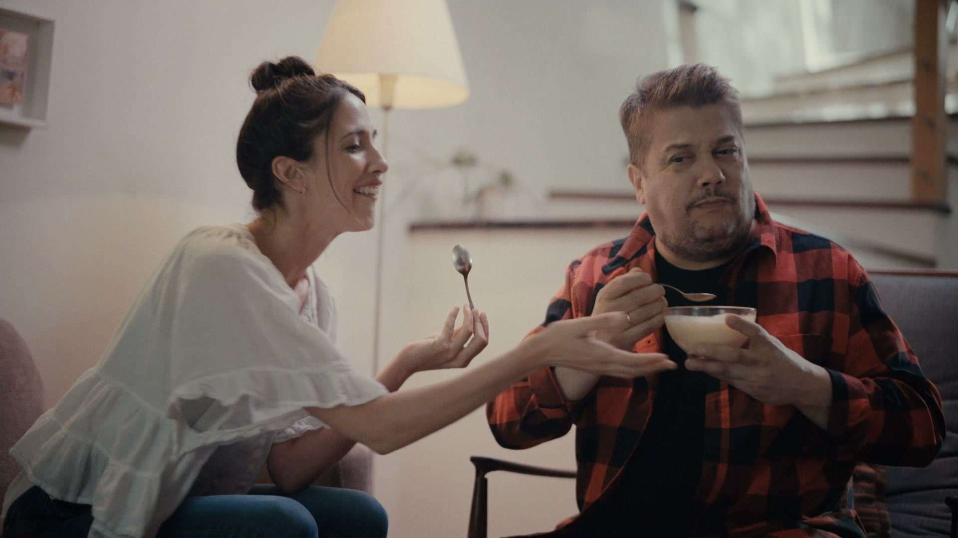 Pareja compartiendo un plato de arroz en el living de su casa