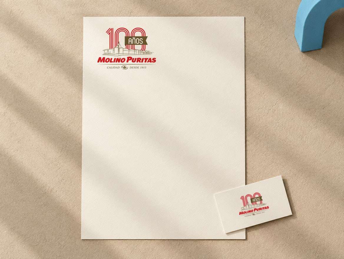 Isologo conmemorativo «100 años» de Molino Puritas, desde 1915, aplicado en una hoja membretada, una tarjeta plegada y una tarjeta personal de papel crema