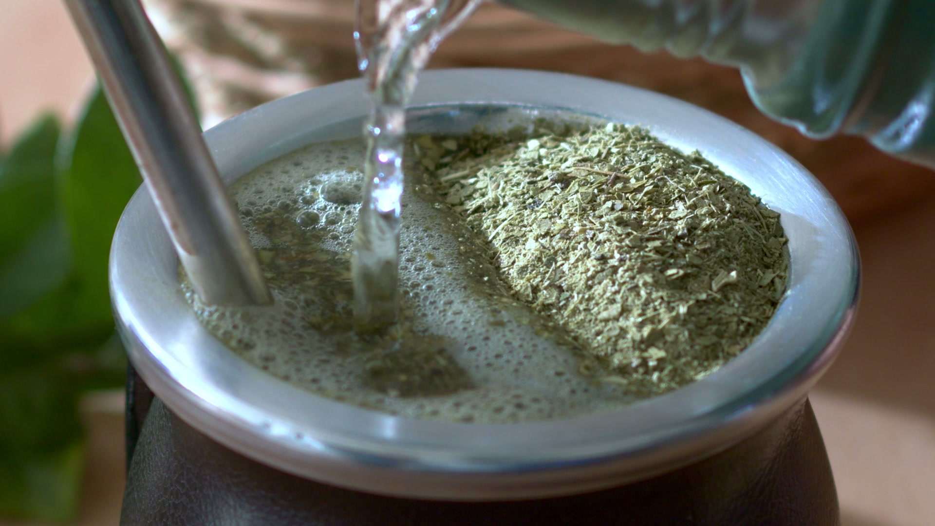 Agua cayendo sobre un mate cebado, con bombilla metálica