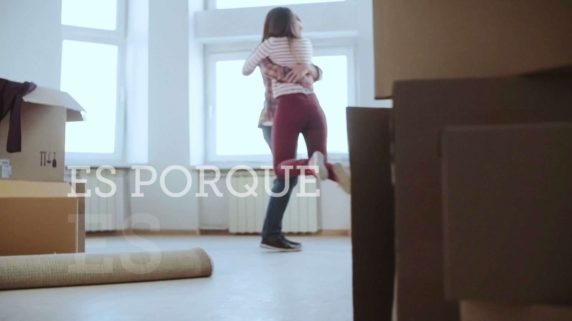 Mujer abrazando a su pareja en un departamento con cajas de mudanza