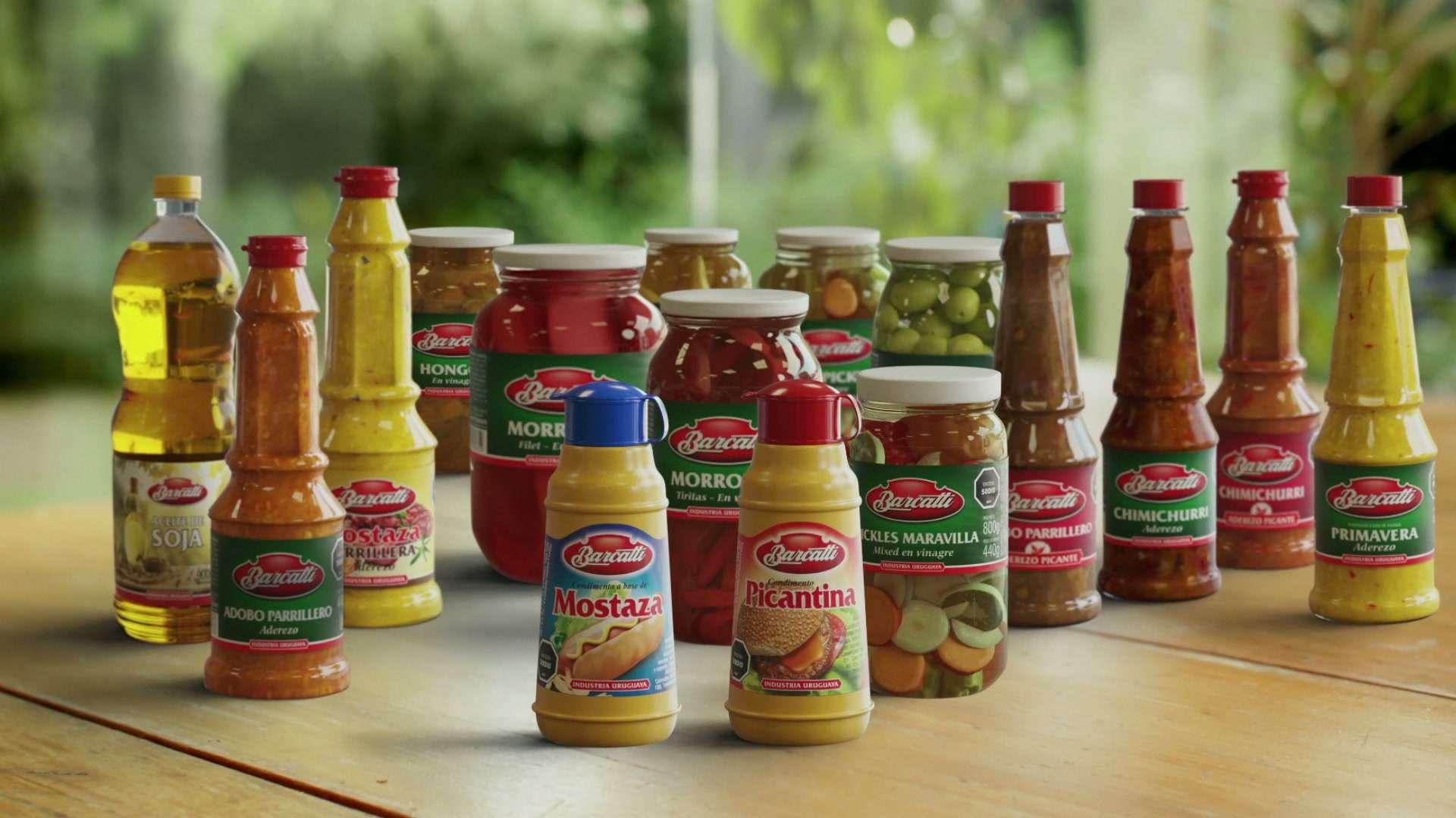 Frascos y botellas de la línea Barcatti: salsas, pickles y aderezos, sobre una mesa al aire libre
